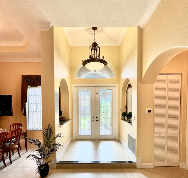 tiled foyer entrance featuring ornamental molding, french doors, and a textured ceiling