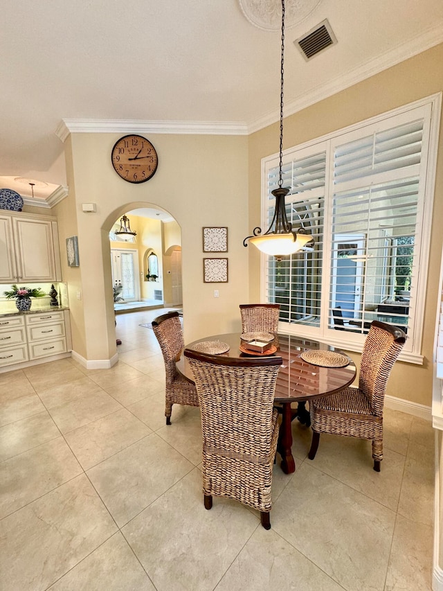 dining area with ornamental molding and light tile patterned flooring