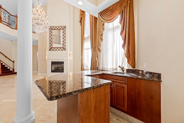 bar with dark stone countertops, a healthy amount of sunlight, and sink