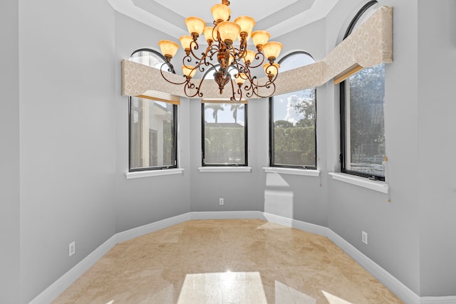 empty room featuring a tray ceiling and a chandelier