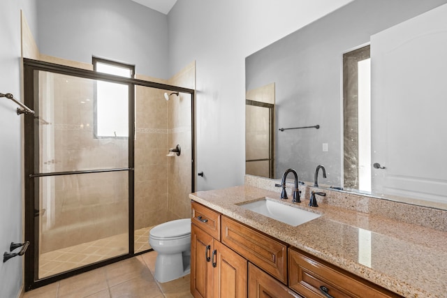 bathroom featuring a shower with door, vanity, toilet, and tile patterned flooring