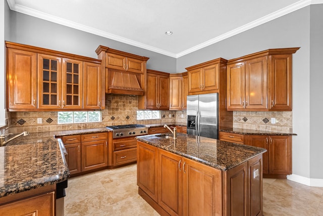 kitchen with decorative backsplash, an island with sink, appliances with stainless steel finishes, dark stone counters, and crown molding