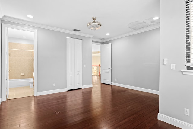 unfurnished bedroom featuring ensuite bath, ornamental molding, and dark hardwood / wood-style flooring