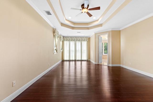 unfurnished room featuring ceiling fan, a tray ceiling, ornamental molding, and dark hardwood / wood-style flooring