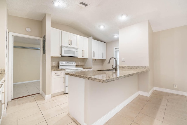 kitchen with lofted ceiling, white cabinets, kitchen peninsula, and white appliances