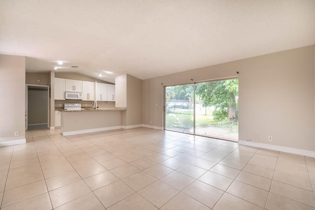 unfurnished living room featuring sink, light tile patterned floors, and vaulted ceiling