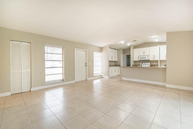 unfurnished living room with vaulted ceiling and light tile patterned floors