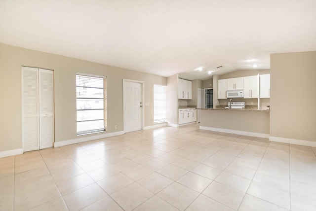 unfurnished living room featuring vaulted ceiling and light tile patterned floors