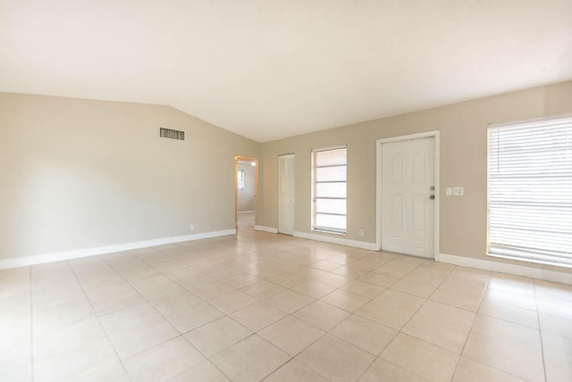 tiled spare room featuring vaulted ceiling