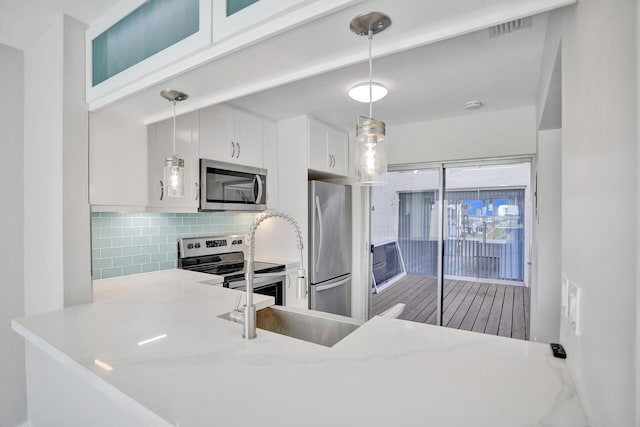 kitchen featuring decorative backsplash, appliances with stainless steel finishes, decorative light fixtures, and white cabinetry