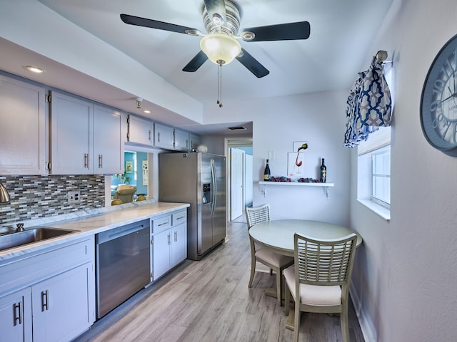 kitchen with pendant lighting, sink, decorative backsplash, light wood-type flooring, and stainless steel appliances