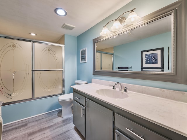 full bathroom with hardwood / wood-style flooring, vanity, toilet, and enclosed tub / shower combo