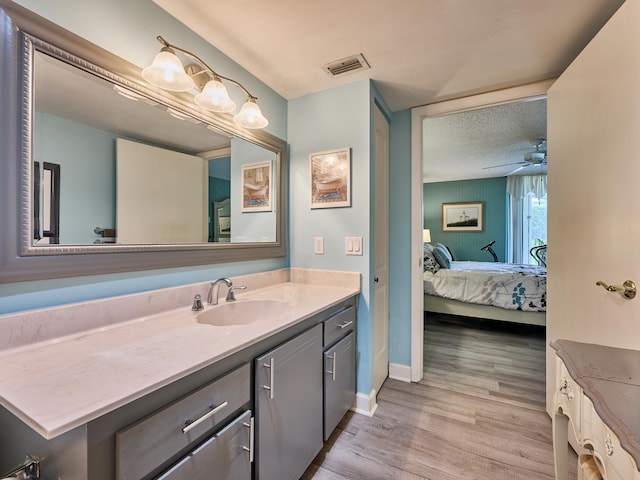 bathroom with ceiling fan, hardwood / wood-style floors, vanity, and a textured ceiling