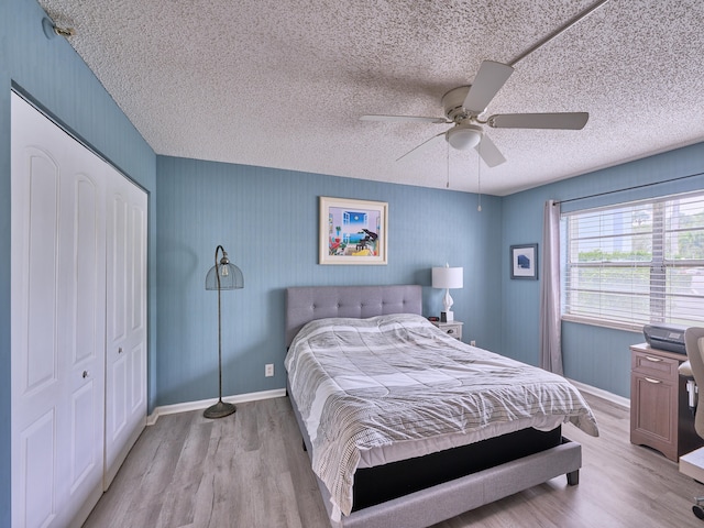 bedroom with ceiling fan, a closet, a textured ceiling, and light wood-type flooring