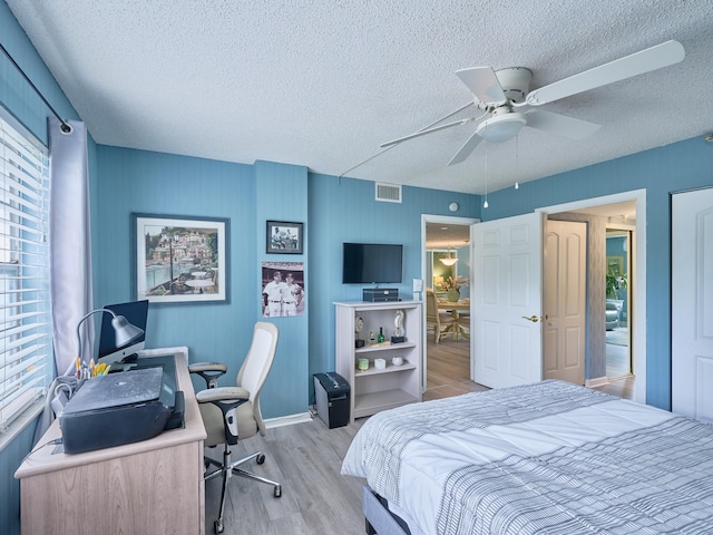 bedroom featuring ceiling fan, light wood-type flooring, and a textured ceiling