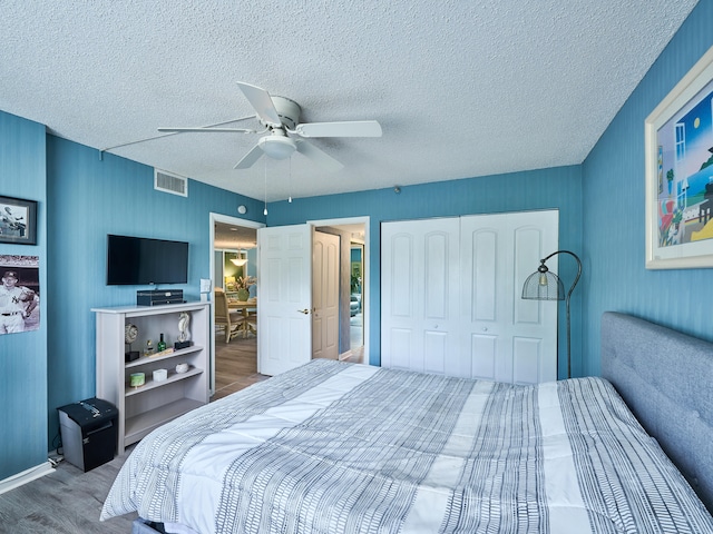 bedroom with hardwood / wood-style floors, a textured ceiling, a closet, and ceiling fan