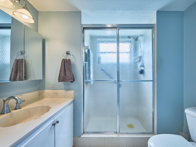 bathroom featuring vanity, toilet, and a shower with shower door