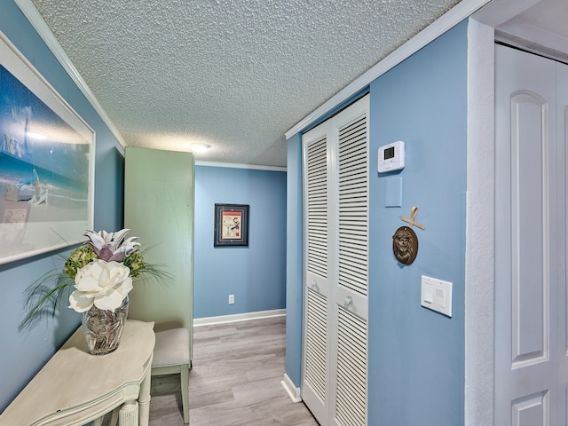 hall with crown molding, light hardwood / wood-style floors, and a textured ceiling