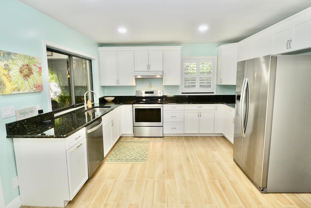 kitchen with sink, light wood-type flooring, white cabinetry, stainless steel appliances, and dark stone countertops