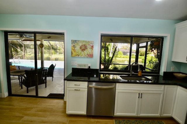 kitchen with dishwasher, light hardwood / wood-style flooring, dark stone countertops, sink, and white cabinets