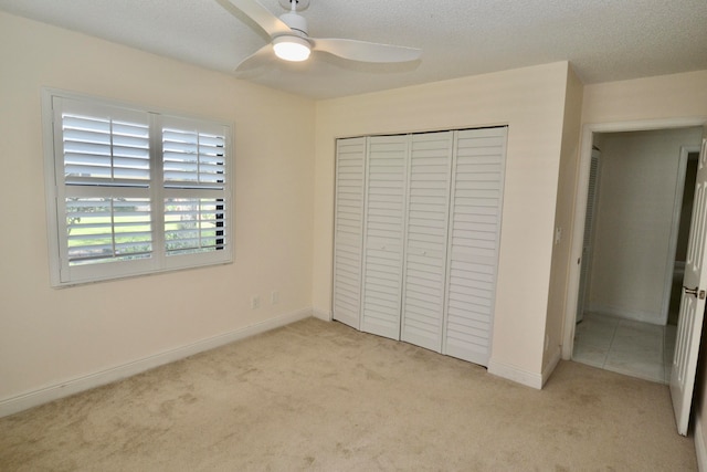 unfurnished bedroom with light carpet, a closet, a textured ceiling, and ceiling fan