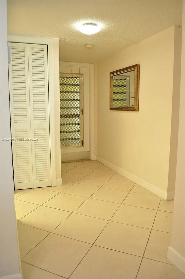 hallway featuring a textured ceiling and light tile patterned floors