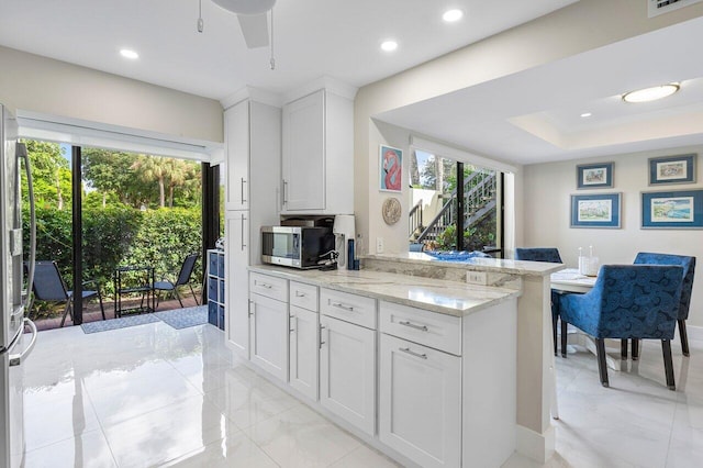 kitchen with a wealth of natural light, white cabinetry, and light stone counters