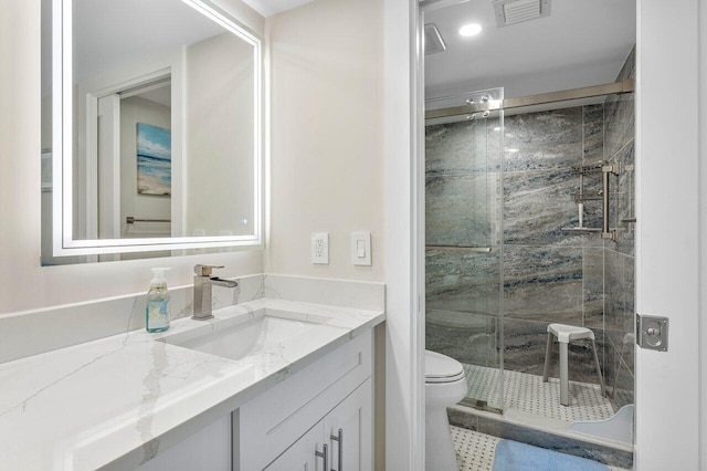 bathroom featuring toilet, vanity, and a shower with door