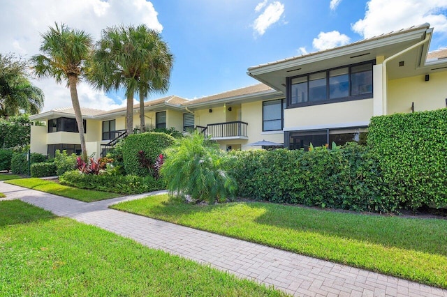 view of front of home featuring a front yard and a balcony