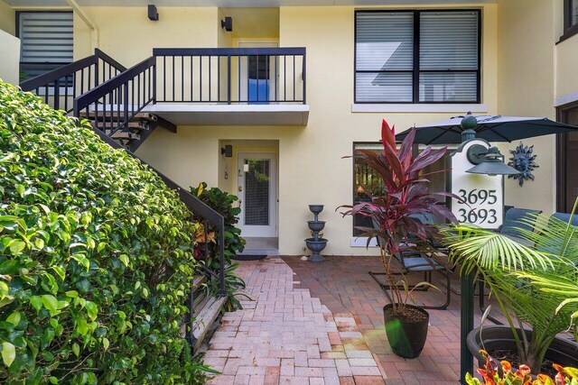 view of exterior entry with a patio area and a balcony