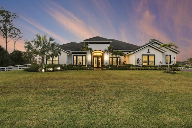 mediterranean / spanish-style house with fence, a lawn, and french doors