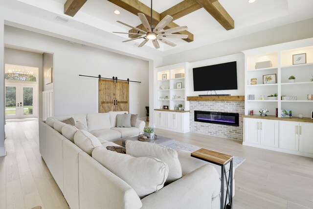 living room with ceiling fan, light hardwood / wood-style floors, beam ceiling, and a brick fireplace