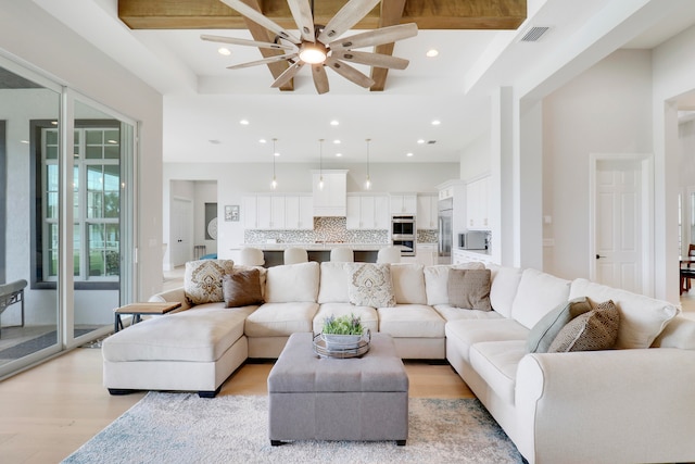 living room featuring beam ceiling, ceiling fan, and light wood-type flooring