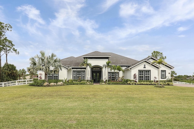 view of front facade featuring french doors, a front yard, fence, and stucco siding