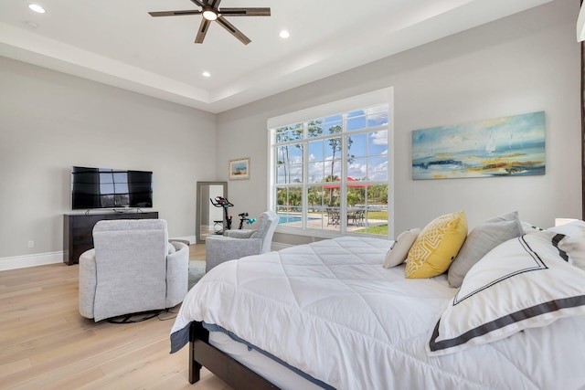 bedroom featuring ceiling fan, a raised ceiling, and wood-type flooring