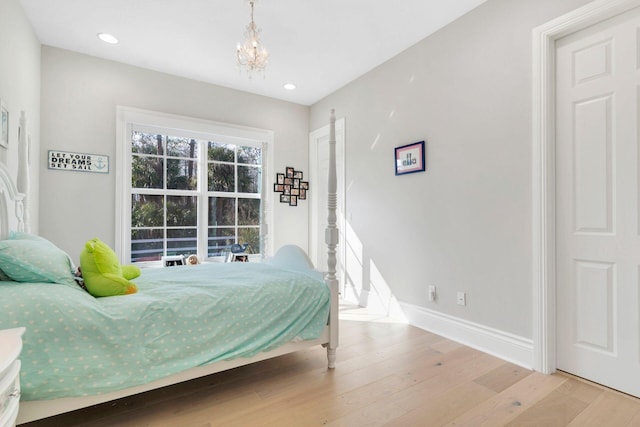 bedroom featuring an inviting chandelier and light hardwood / wood-style flooring