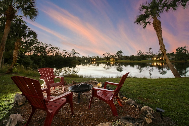 exterior space featuring a lawn, a water view, and an outdoor fire pit