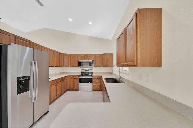 kitchen with appliances with stainless steel finishes, lofted ceiling, sink, and light tile patterned floors