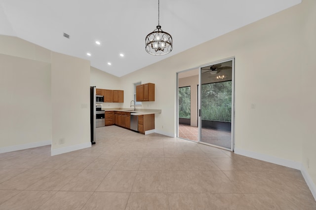 kitchen featuring lofted ceiling, sink, light tile patterned flooring, decorative light fixtures, and appliances with stainless steel finishes