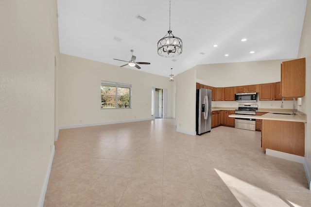 kitchen featuring light tile patterned floors, appliances with stainless steel finishes, high vaulted ceiling, ceiling fan with notable chandelier, and pendant lighting