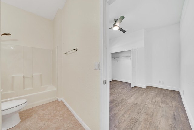 bathroom featuring toilet, shower / washtub combination, hardwood / wood-style flooring, and ceiling fan