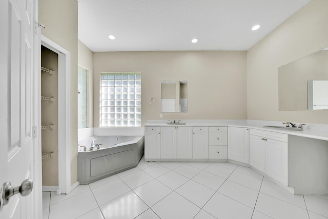 bathroom with vanity, a textured ceiling, a washtub, and tile patterned flooring