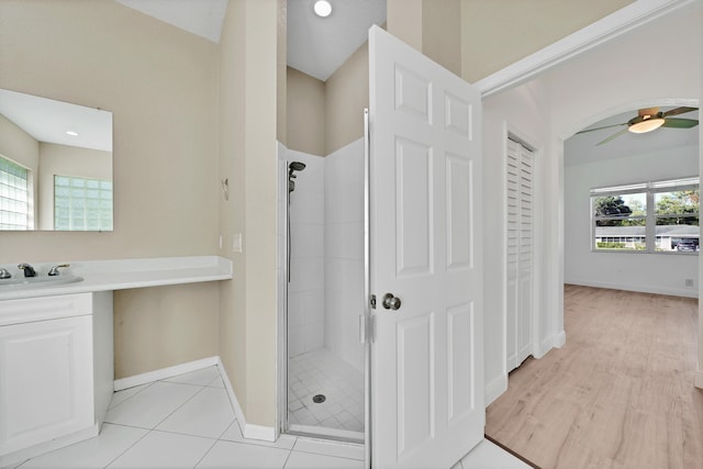 bathroom with vanity, a healthy amount of sunlight, ceiling fan, and tiled shower