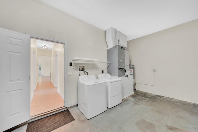 washroom featuring gas water heater, washing machine and dryer, and heating unit