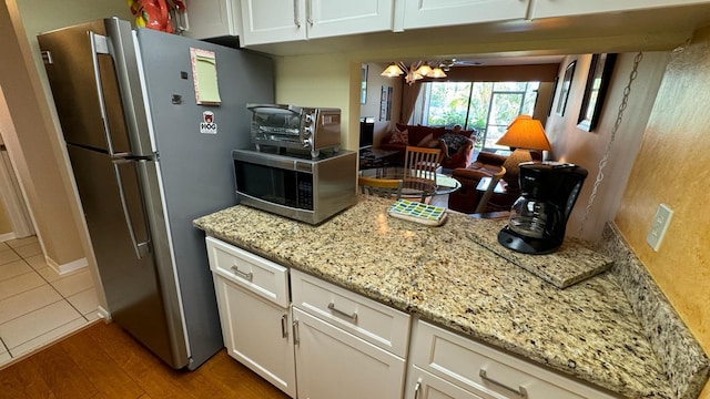 kitchen with light stone counters, hardwood / wood-style flooring, appliances with stainless steel finishes, and white cabinets