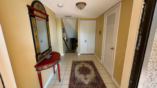 corridor with light tile patterned flooring and a textured ceiling