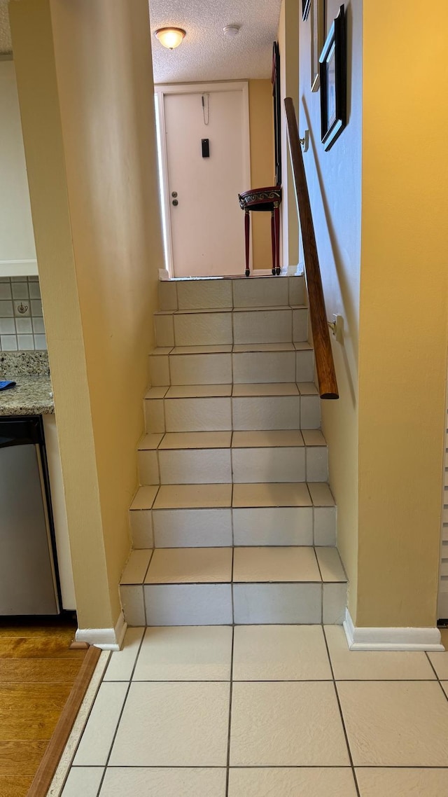 stairway featuring tile patterned floors and a textured ceiling