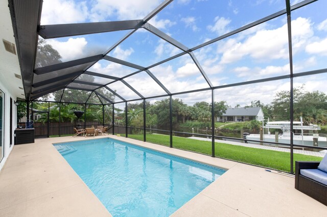 pool with a lawn, glass enclosure, and a patio area