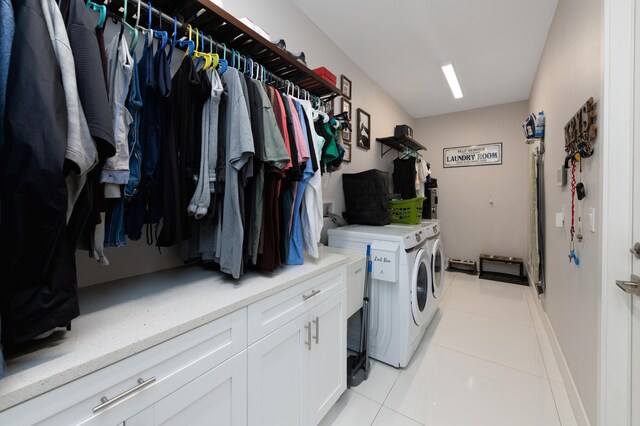 clothes washing area with light tile patterned floors, cabinet space, and independent washer and dryer