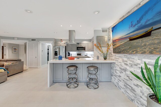 kitchen featuring a kitchen breakfast bar, kitchen peninsula, stainless steel appliances, and gray cabinetry